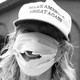 A woman wearing a Make America Great Again hat and a mask with a hole.