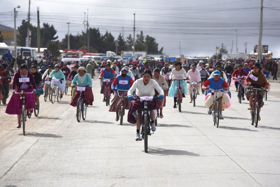 Indigenous Bolivian women ride bicycles during a race.