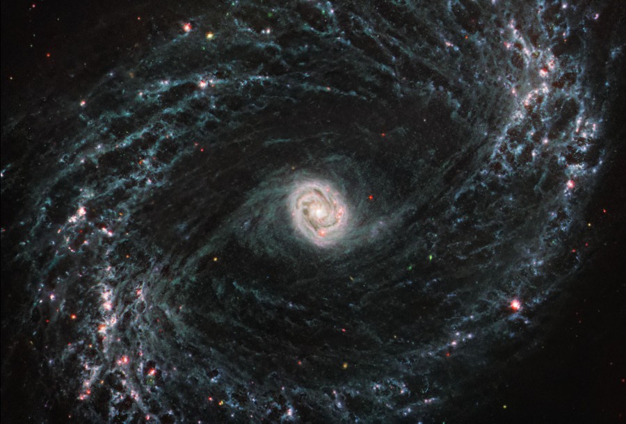 A view of a galaxy shaped like a small spiral within a much lager spiral.