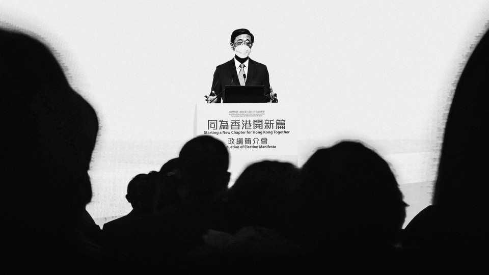 John Lee, wearing a mask, stands behind a lectern to deliver a speech.