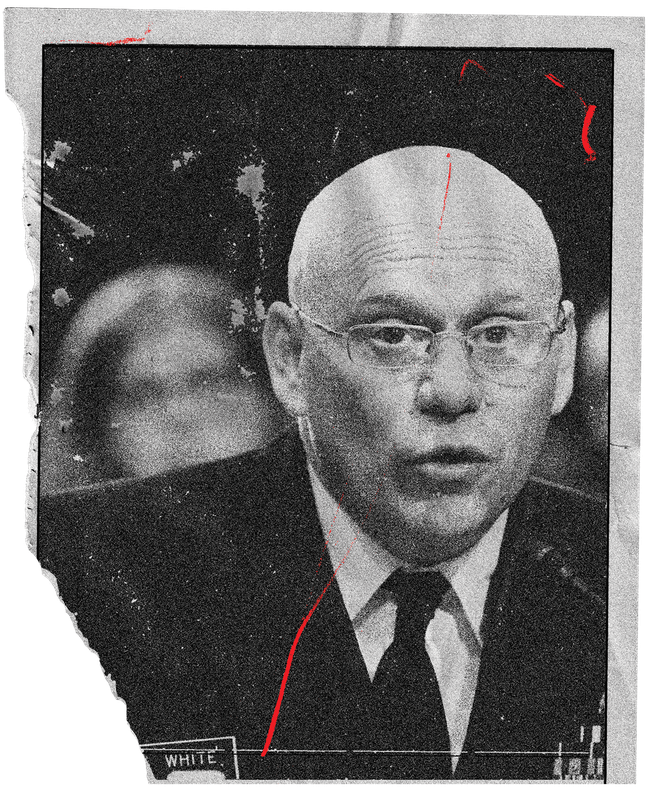 photo of bald man wearing glasses, suit, and tie speaking