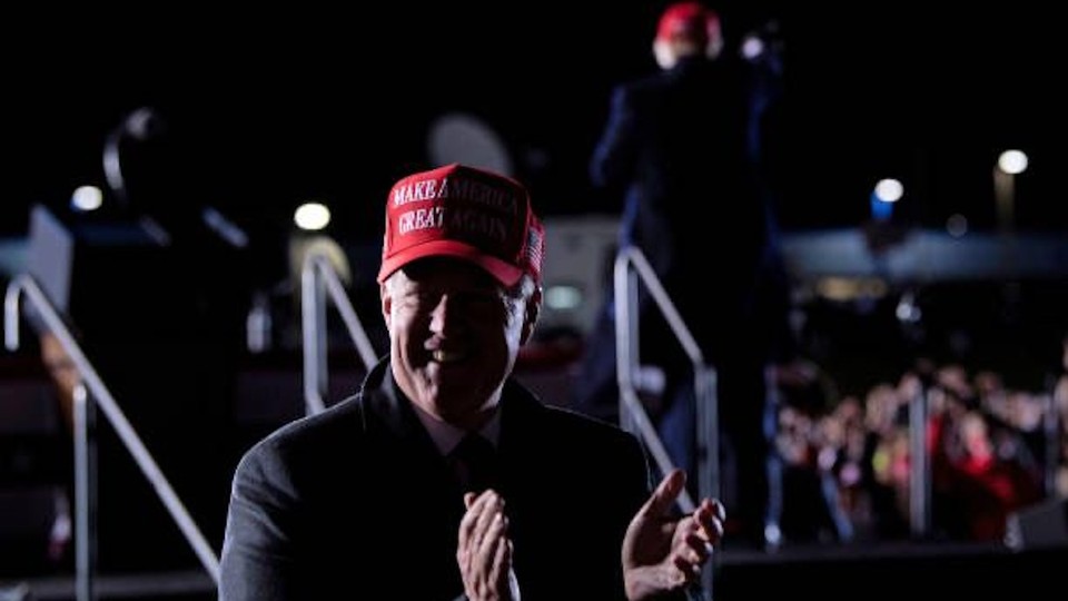 man wearing Make America Great Again hat smiles and claps