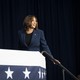 Kamala Harris smiles and walks up steps at a campaign event.
