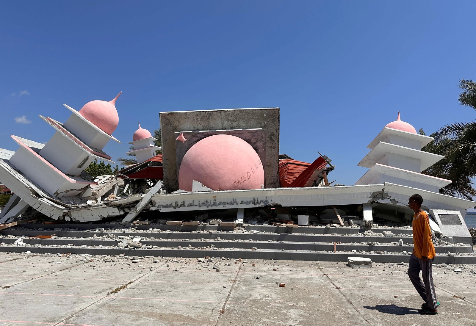 A man walks past a collapsed mosque, after an earthquake.
