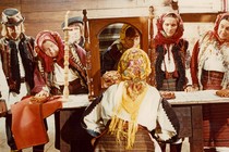 A still from "Shadows of Forgotten Ancestors" in which several people stare at a woman who is looking at herself in a mirror