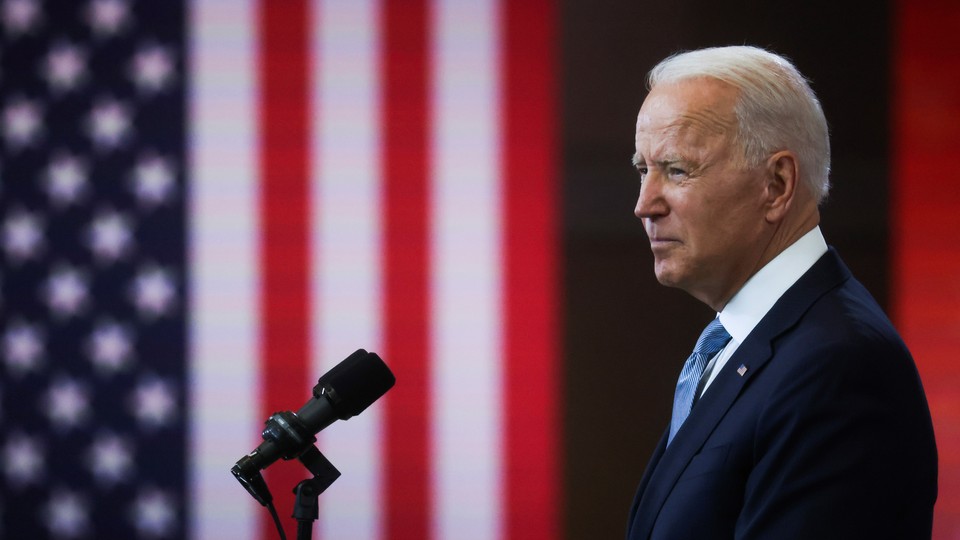 Biden speaking, flanked by American flags