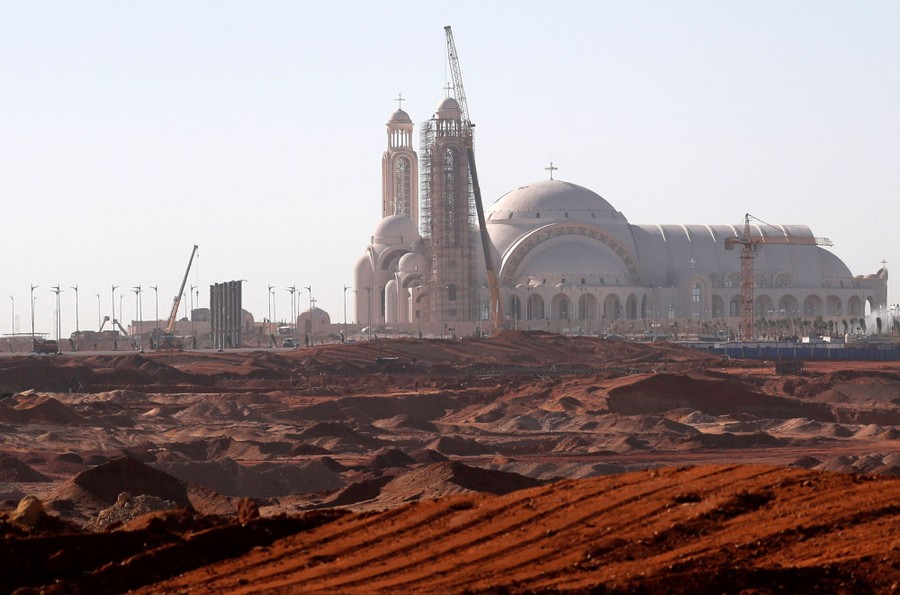 A huge cathedral is seen under construction in a desert area.