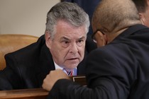Representative Peter King of New York speaking with a colleague in a congressional hearing room