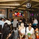 A group of adults watching "Love Island USA" in a bar with their backs turned toward the camera