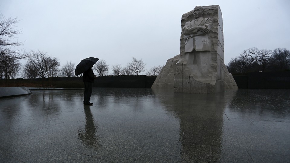 A person, carrying an umbrella, at the Martin Luther King Jr. Memorial in Washington, D.C.