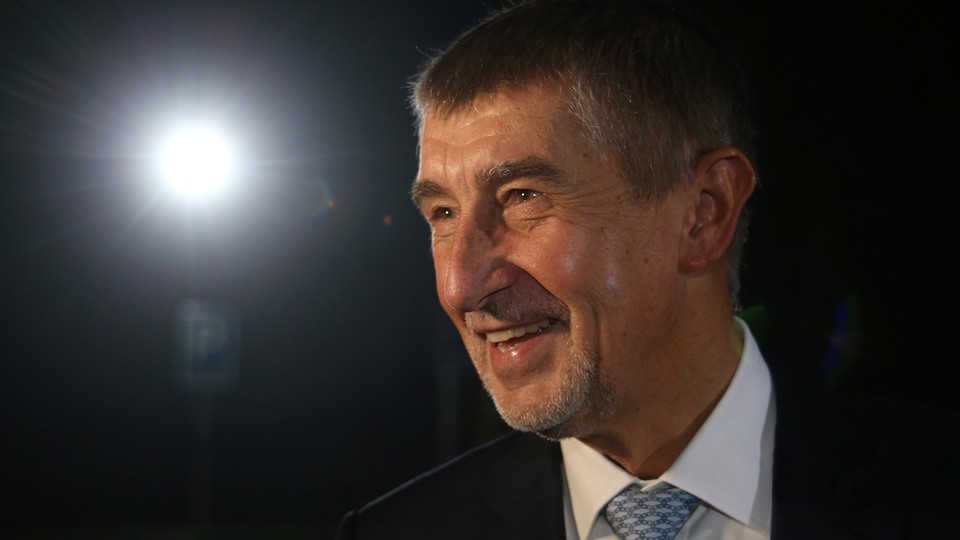 Andrej Babis against a black background with a light shining on him.