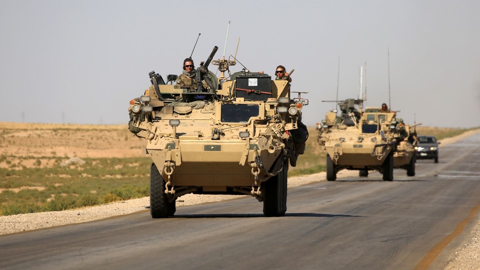 U.S. troops sit atop an armored vehicle on a road near the northern Syrian village of Ain Issa on June 3, 2017.