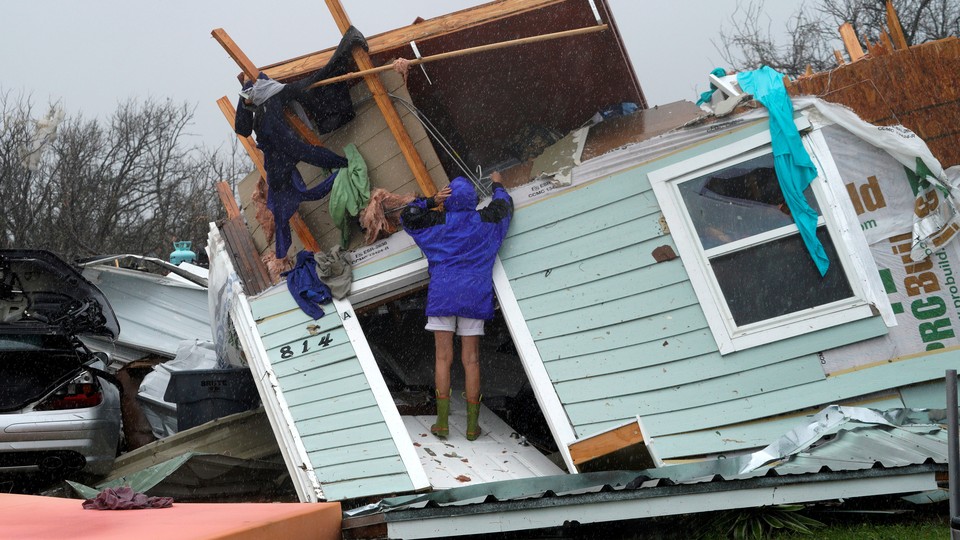 A woman stands on a destroyed house in Fulton, Texas.