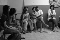 An Israeli family and neighbors sit in chairs and on the floor in a Jerusalem bomb shelter.