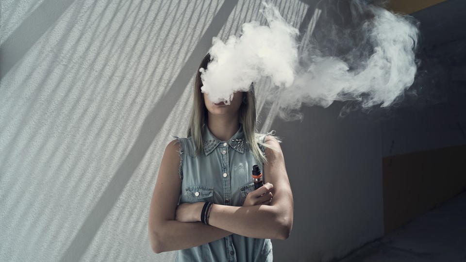 A woman's face is obscured by a cloud of vape smoke.