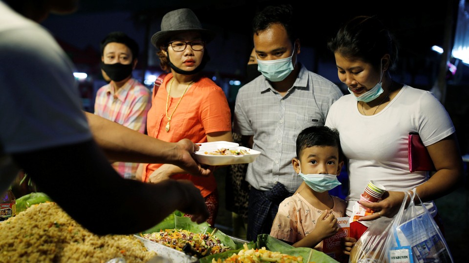 A family wearing face masks buys food from a stall in Yangon, Myanmar.