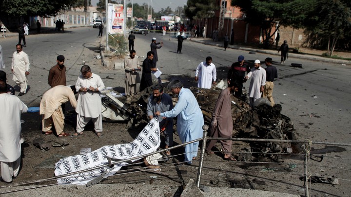 Police and rescue officials cover a body after a blast in Quetta, Pakistan on June 23, 2017.