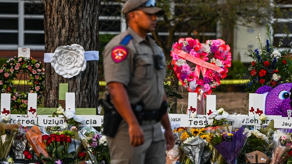 A police officer stands near a makeshift memorial for the shooting victims outside Robb Elementary School in Uvalde, Texas.