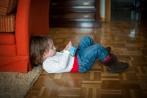 A child on the floor looking at a smartphone