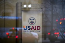 A sign for USAID with traffic reflected in a window