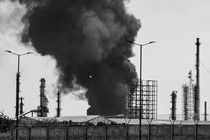Black-and-white photograph of smoke rising over an oil refinery in Tehran