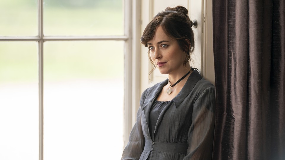 A scene from the film "Persuasion," depicting Dakota Johnson as Anne Elliott, sitting by a large window