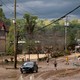 Four people walk through a muddy suburban street intersection, inspecting the flood damage in Asheville, North Carolina, in the aftermath of Hurricane Helene