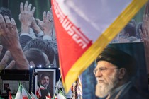 A color photo showing portraits of Ayatollah Ali Khamenei displayed alongside Iranian flags at a rally.