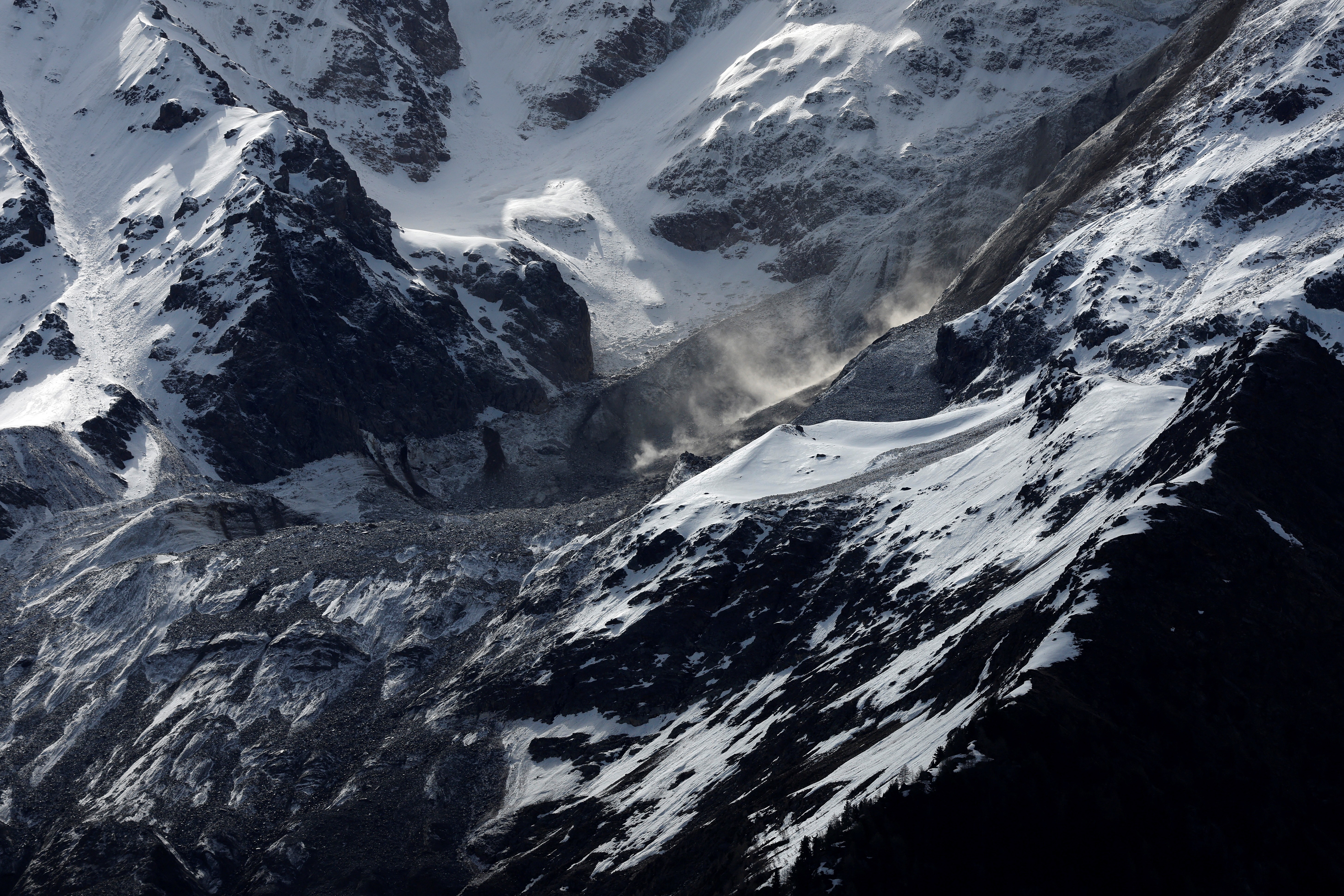 Dust swirls above a mountainside glacier.