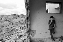 A Palestinian youth smokes, leaning against the wall of a ruined house amid rubble in Khan Younis, Gaza, October 2003.