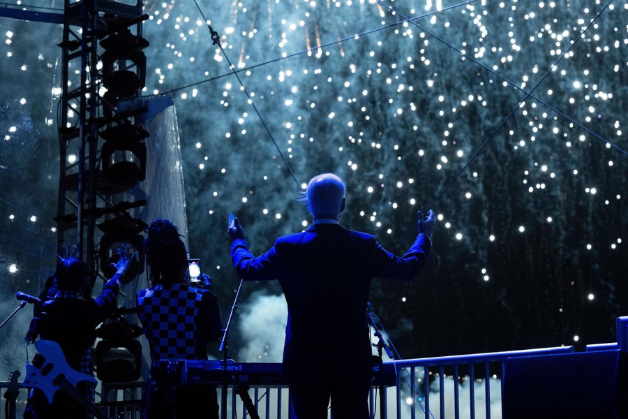 President Joe Biden raises his arms as he watches fireworks.