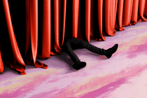 Legs are seen next to a red curtain