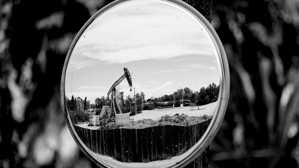 An oil pumpjack is reflected in a mirror as it operates on August 5, 2022, near Ventura, California.