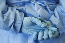 A nurse's gloved hands clasped behind back