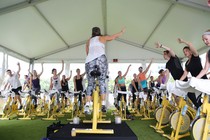 People ride yellow stationary bikes in an outdoor SoulCycle class.