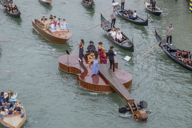 A violin-shaped boat parades near the Accademia Bridge in Venice, Italy.