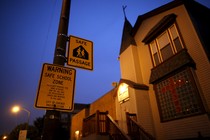 Taken at night, the photo shows a yellow safe-passage sign reading "Warning Safe School Zone" 