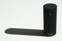 An Amazon Tap sits on a white tabletop.
