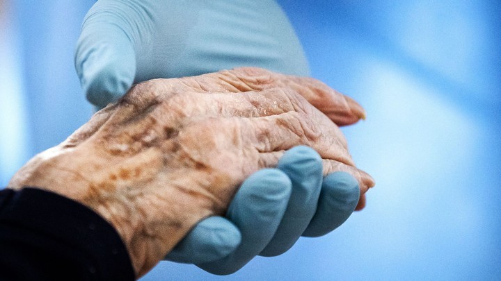 A doctor holds a patient's hand against blue background