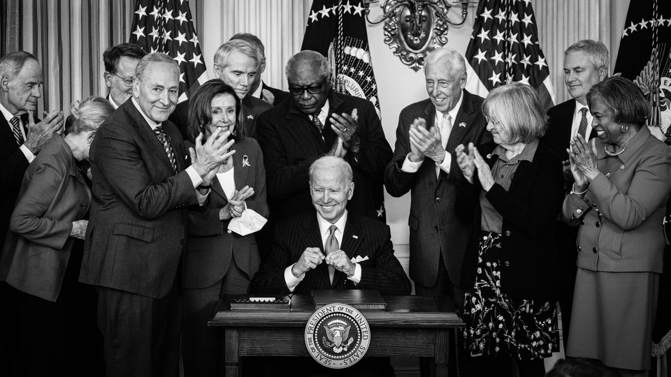 President Biden surrounded by lawmakers while signing legislation
