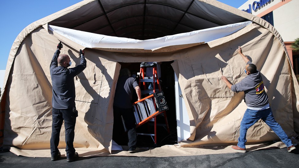 Workers take down an overflow patient care tent