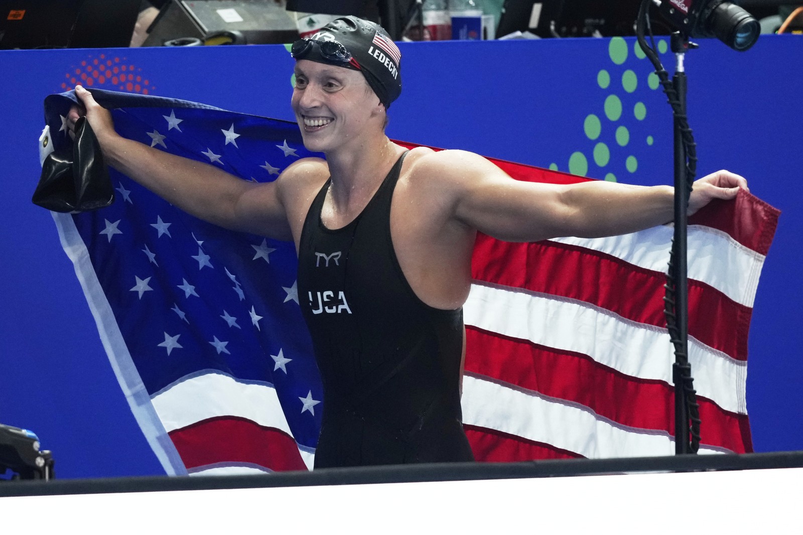 Swimmer Katie Ledecky poses with the American flag after winning a gold medal in a race.