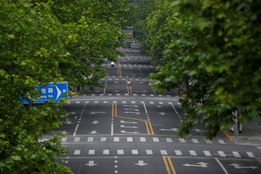 A man takes a picture in the middle of an empty city street.