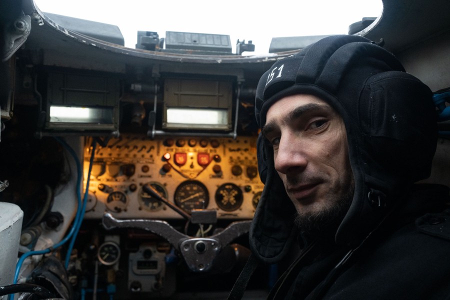 A soldier sits inside an armored vehicle.