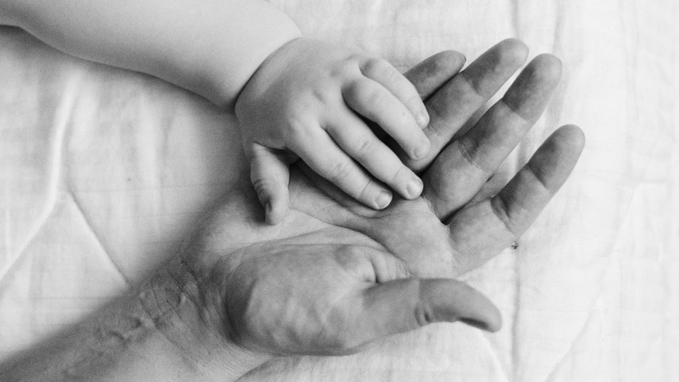 A child's hand is placed upon an adult's
