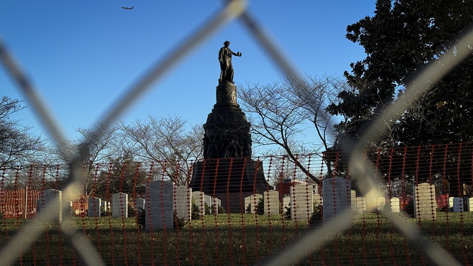 A photo of the Confederate Memorial in Arlington Cemetery, captured through a chain-link fence