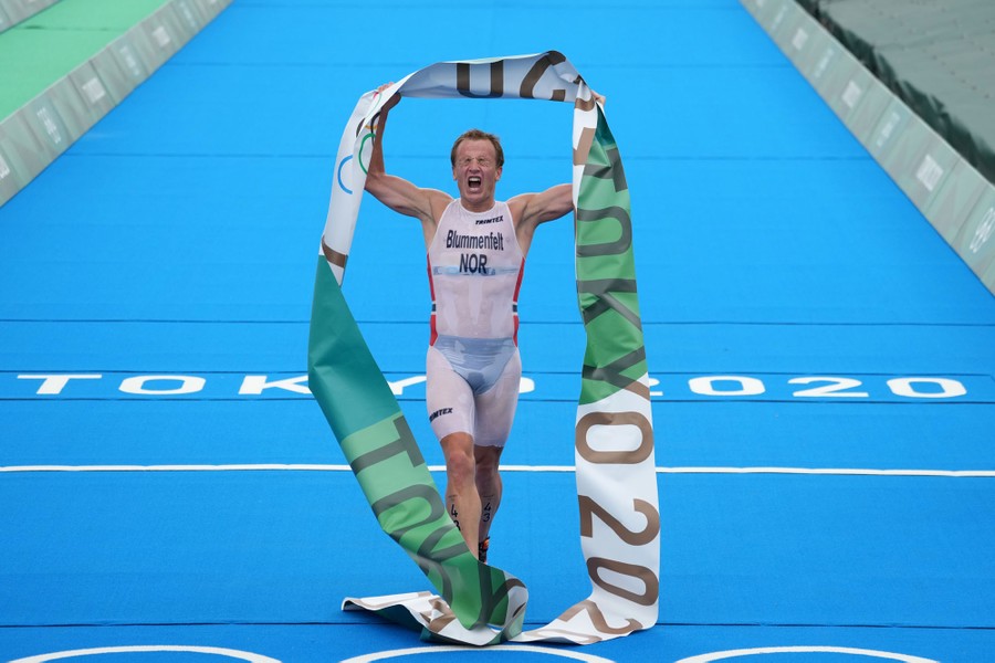 An athlete reacts, crossing a finish line alone.