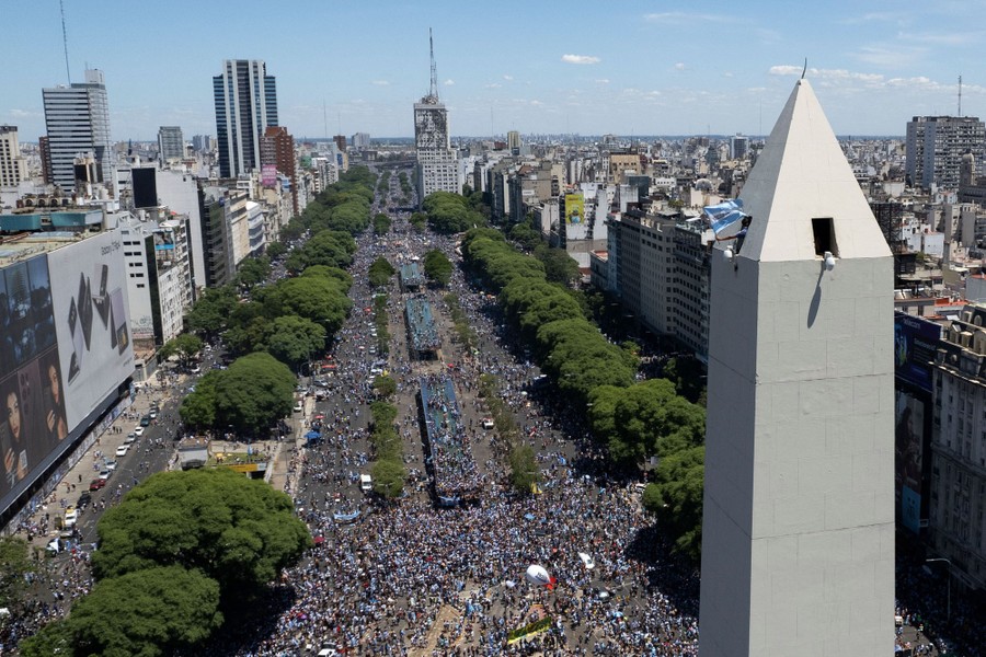 An aerial view of broad city streets and squares filled with people.