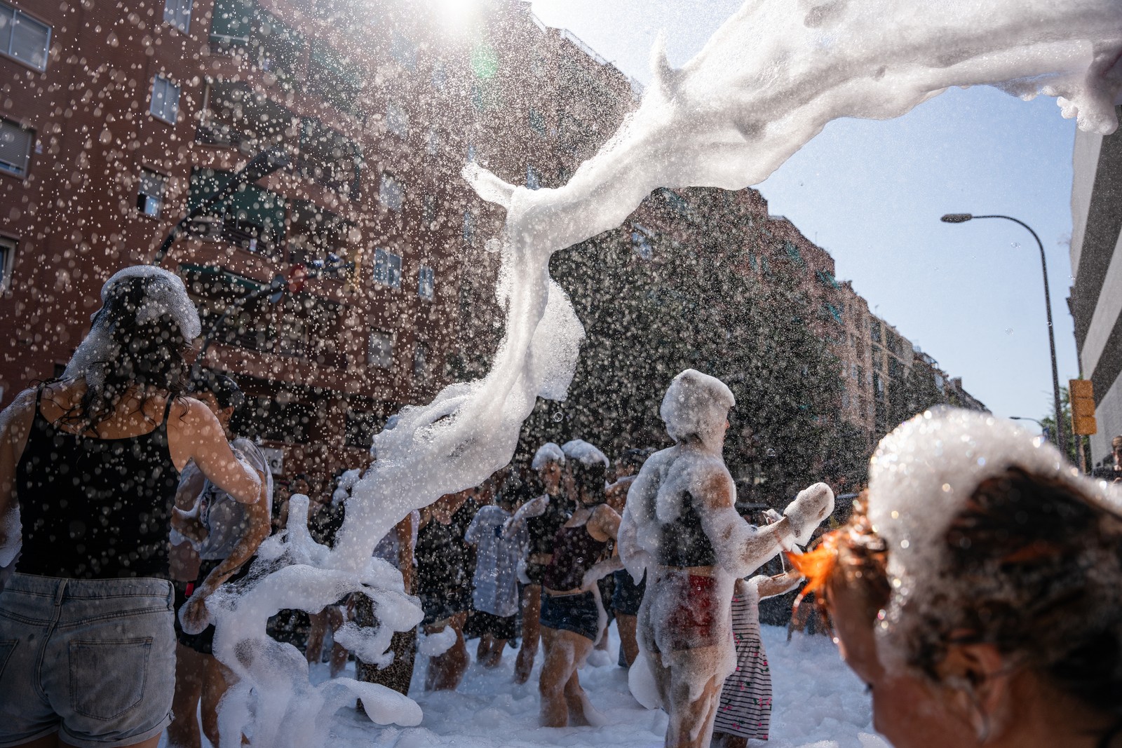 People have fun with water and foam in a street during a heatwave
