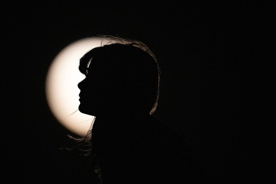 The profile of a person in silhouette in front of a full moon